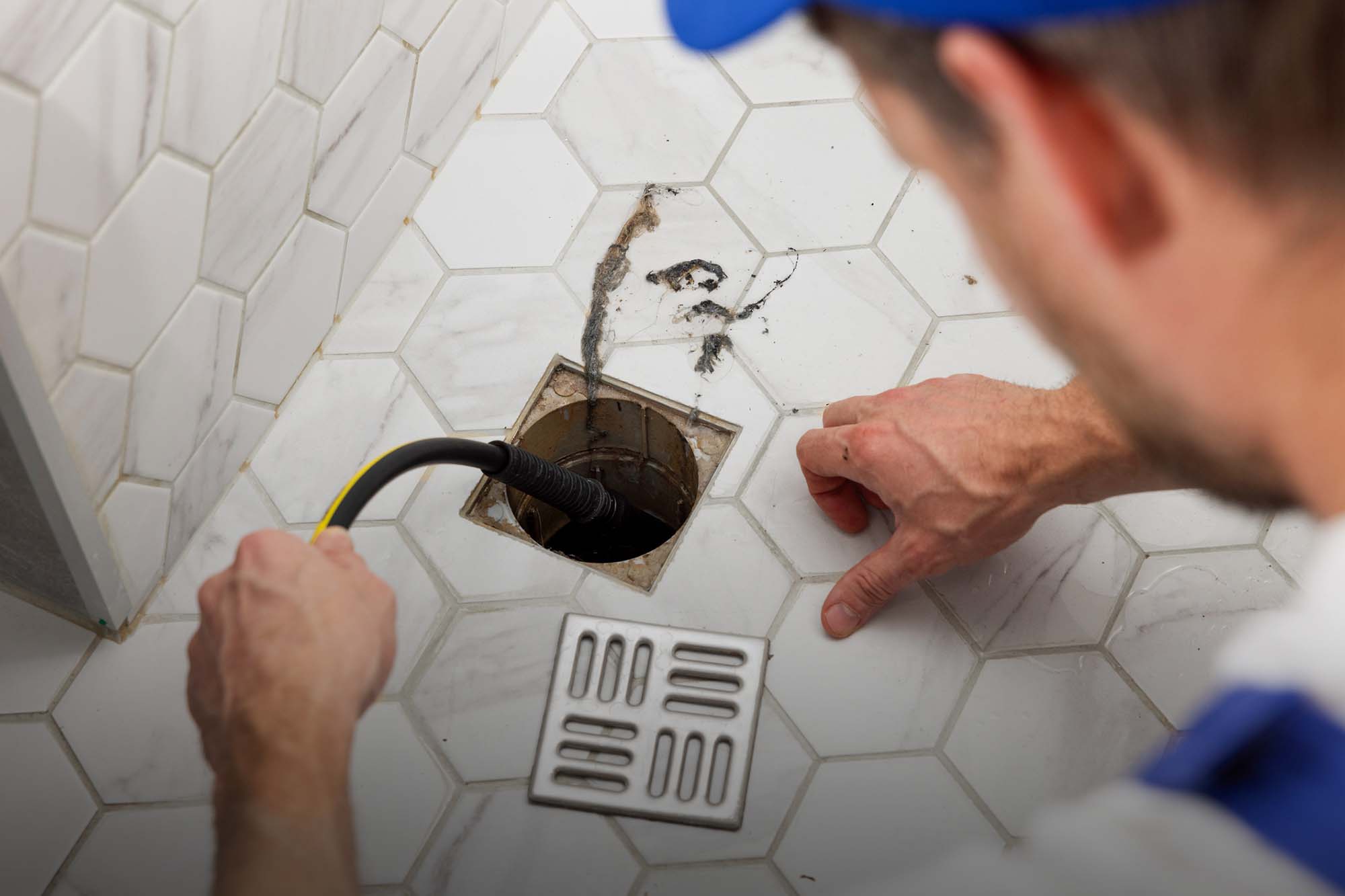 Plumber unclogging blocked shower drain with hydro jetting at home bathroom. sewer cleaning service